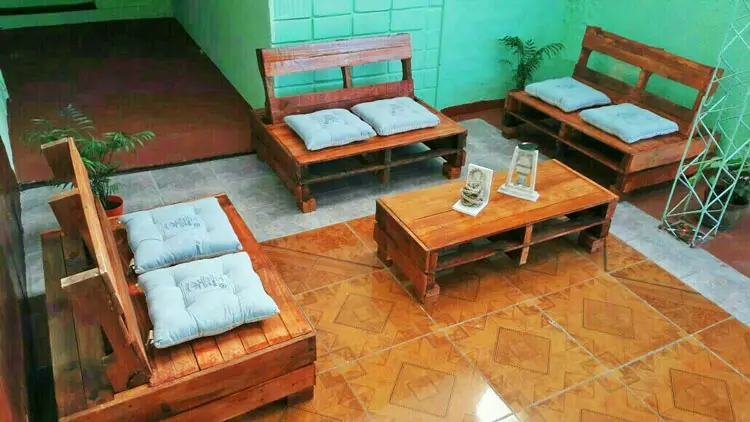 Sofás de paletes com almofadas verdes e mesa de centro