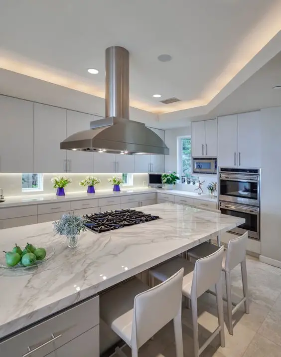 Cozinha com ilha de mármore e cozinha branca