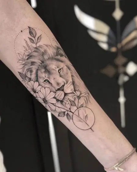 Tatuagem feminina no braço de leão e flores