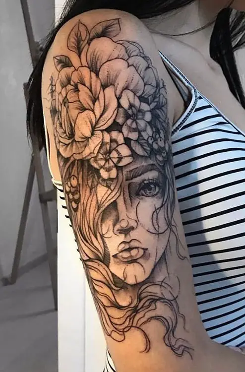 Tatuagem no braço com rosto de mulher e flores