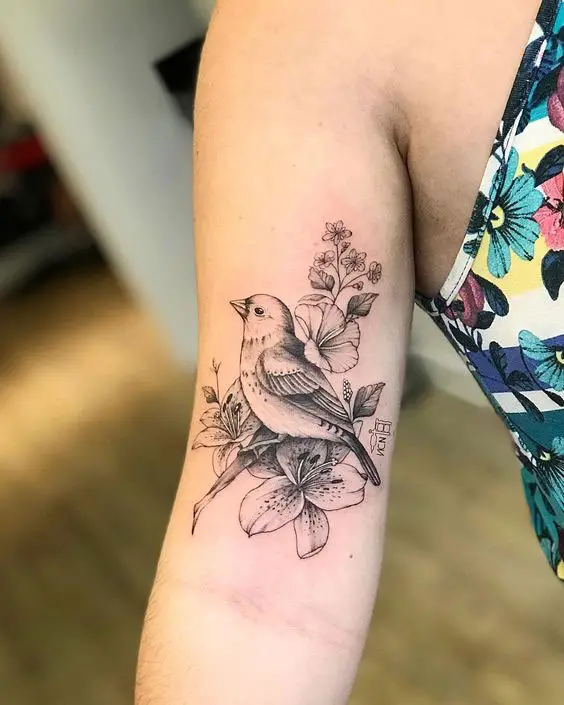 Tatuagem no braço de pássaro e flores