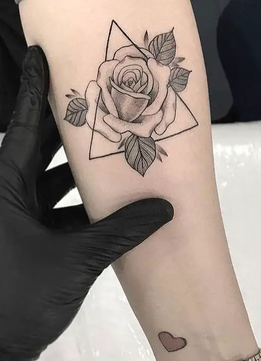 Tatuagem feminina no braço com rosa e triângulo