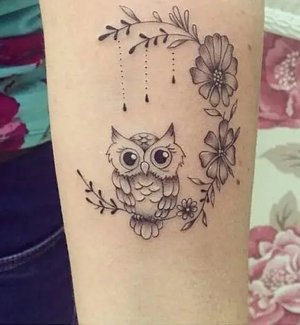 Tatuagem no braço de coruja e flores