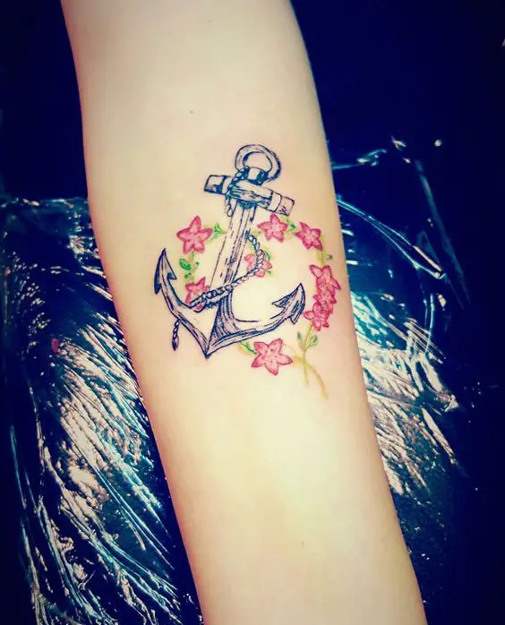 Tatuagem feminina no braço de âncora e flores