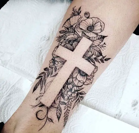 Tatuagem no braço de cruz e flores