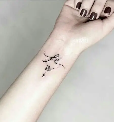 Tatuagem no braço com a palavra fé