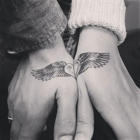 Tatuagens de casal na mão com coração e asas