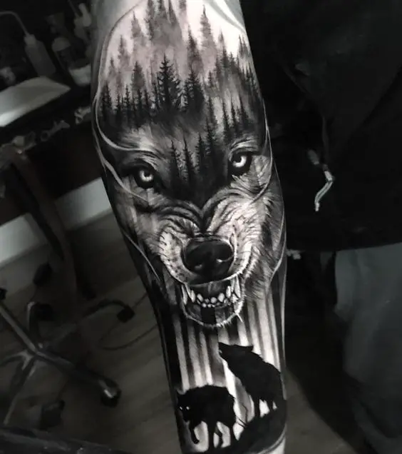 Tatuagem com face de lobo em destaque e silhueta de lobosTatuagem com face de lobo em destaque e silhueta de lobos
