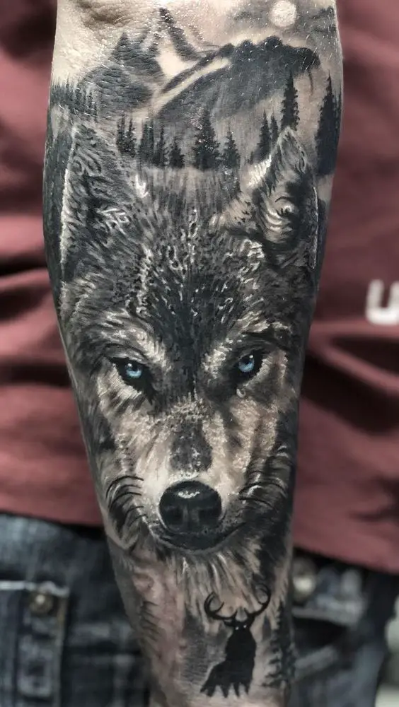 Tatuagem com face de Lobo no Braço com pinheiros, montanhas e lua