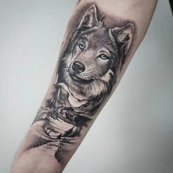 Tatuagem de Lobo, floresta e montanha no antebraço