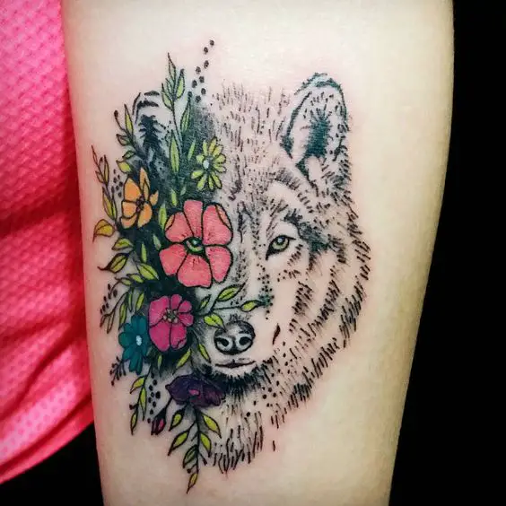 Tatuagem colorida de Lobo com flores no antebraço