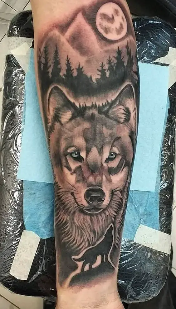 Tatuagem de Lobo na floresta com Lua ao fundo no Braço