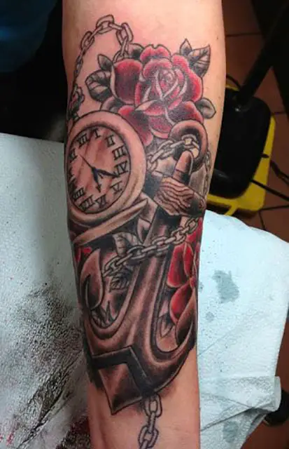 Tatuagem com rosa, relógio e âncora no antebraço